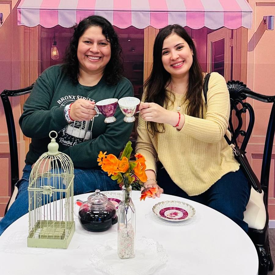 Dos mujeres sonríen y brindan con tazas de té
